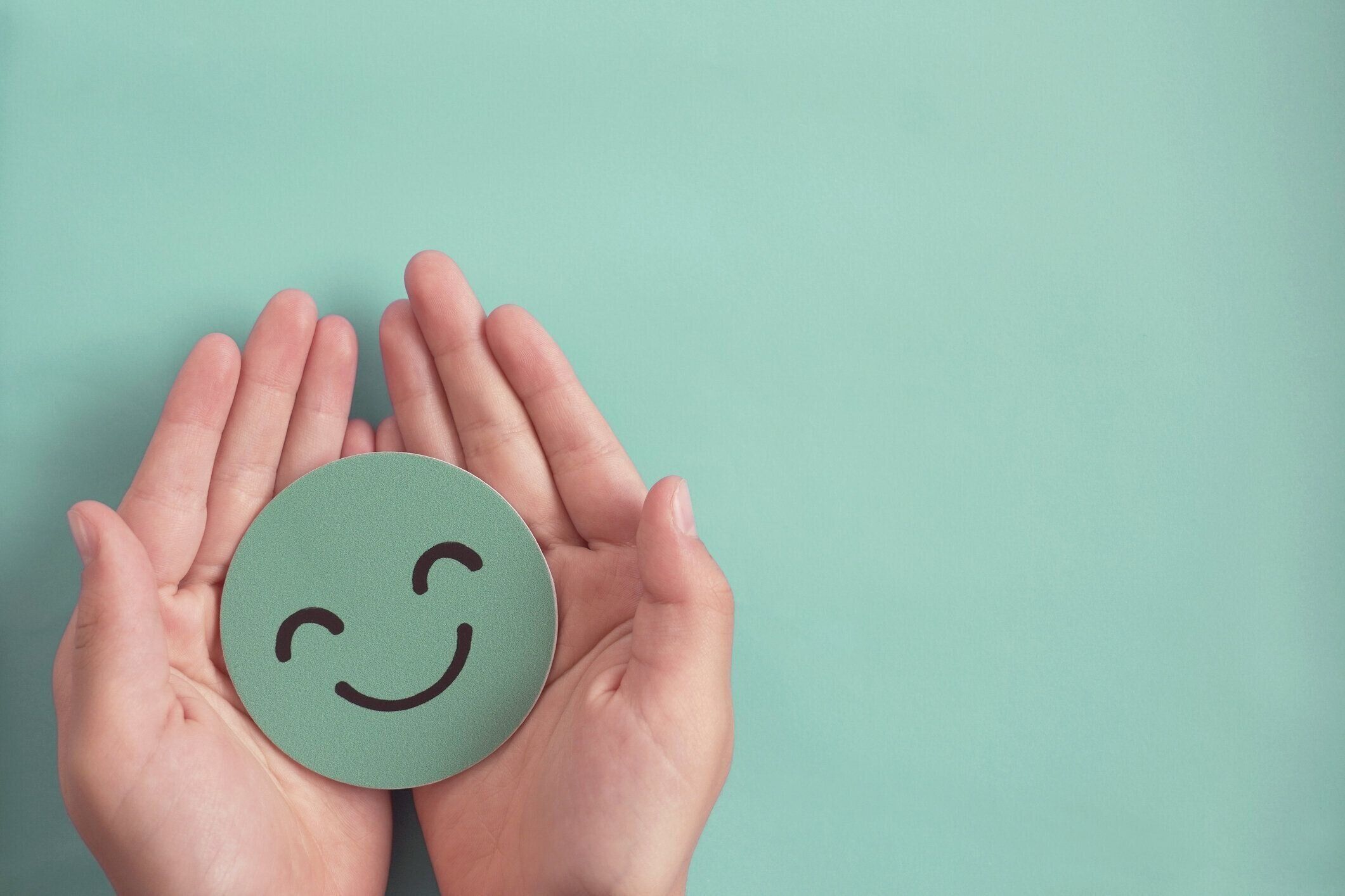 緑の幸せな笑顔の顔の紙カット、良いフィードバック評価と肯定的な顧客レビュー、経験、満足度調査、メンタルヘルス評価、子供の健康、世界のメンタルヘルスデーの概念を保持する手