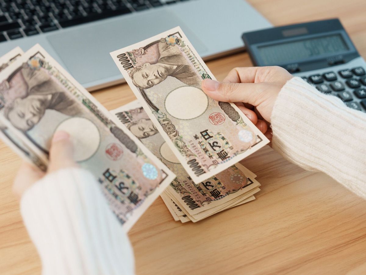 電卓で日本円紙幣を数える女性。千円のお金。日本の現金、税金、不況経済、インフレ、投資、金融、給与、支払いのコンセプト