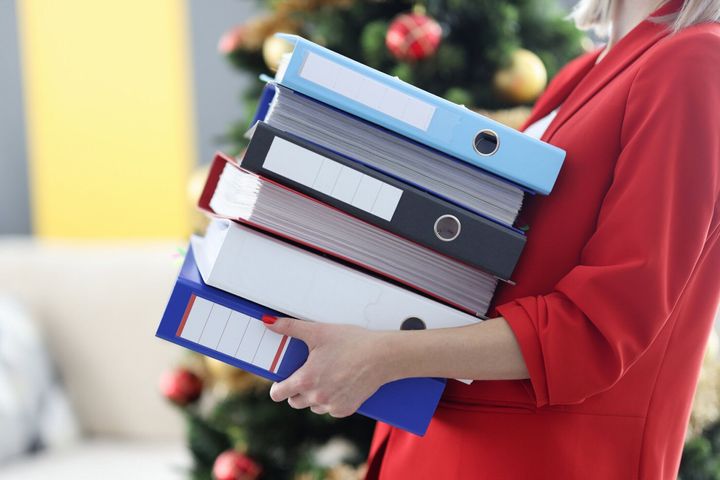 女性は文書とフォルダの重いスタックを保持しています。