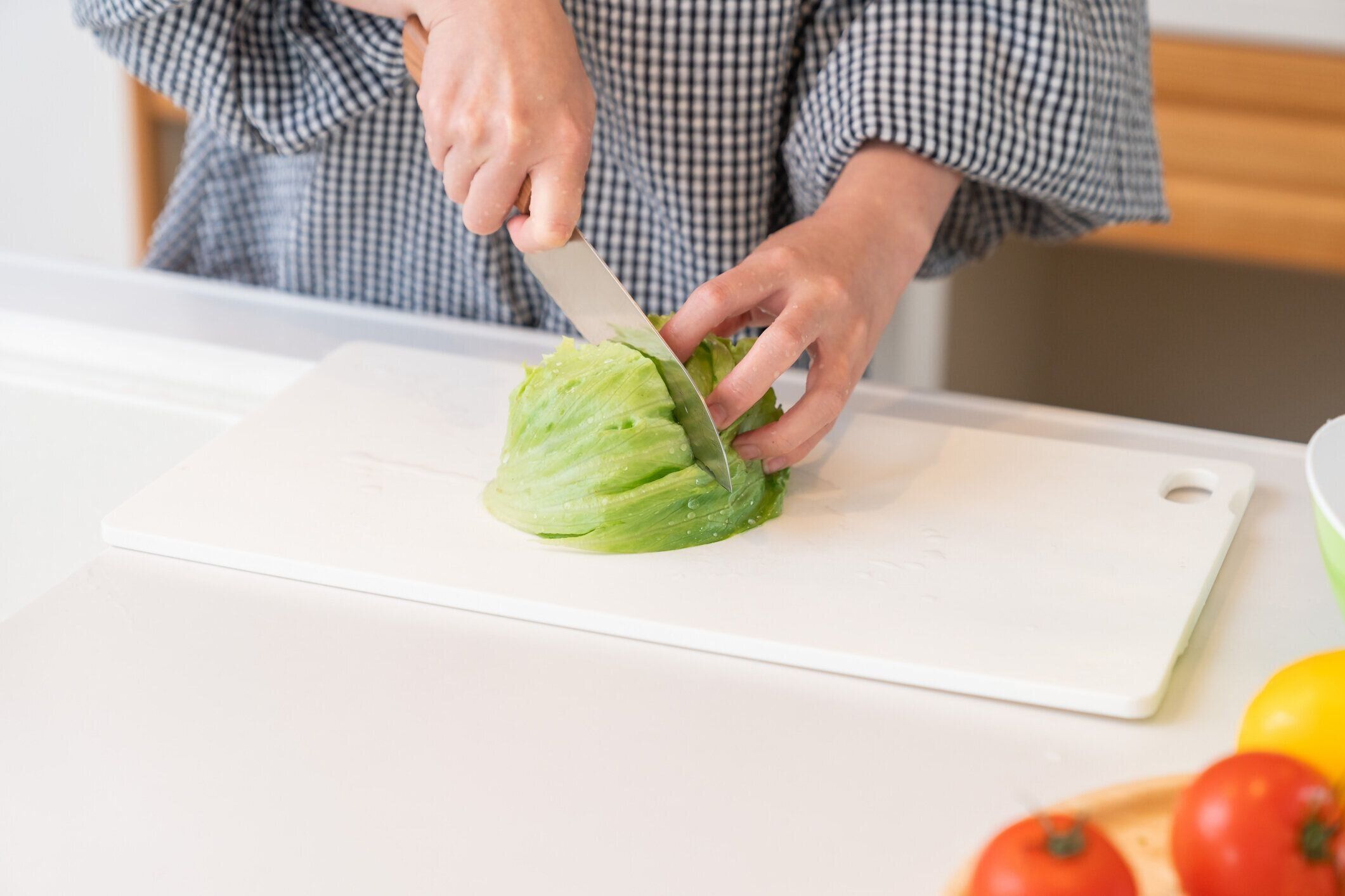 女性は台所で料理をし、レタスを切る手