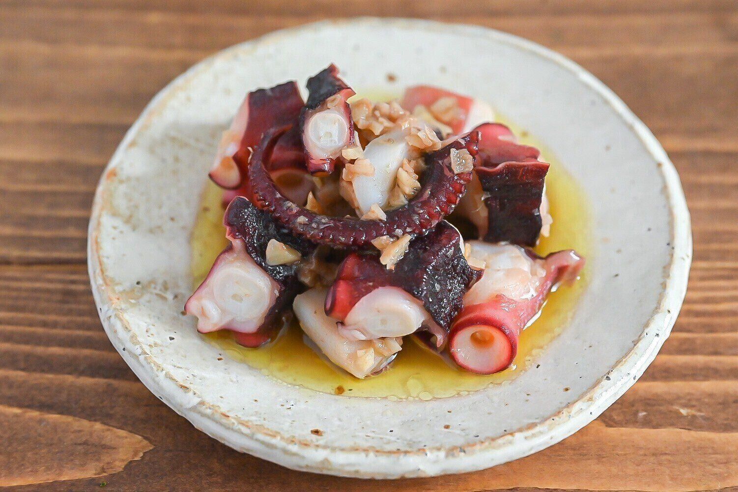 陶器の皿に盛られたたこのアンチョビ炒め