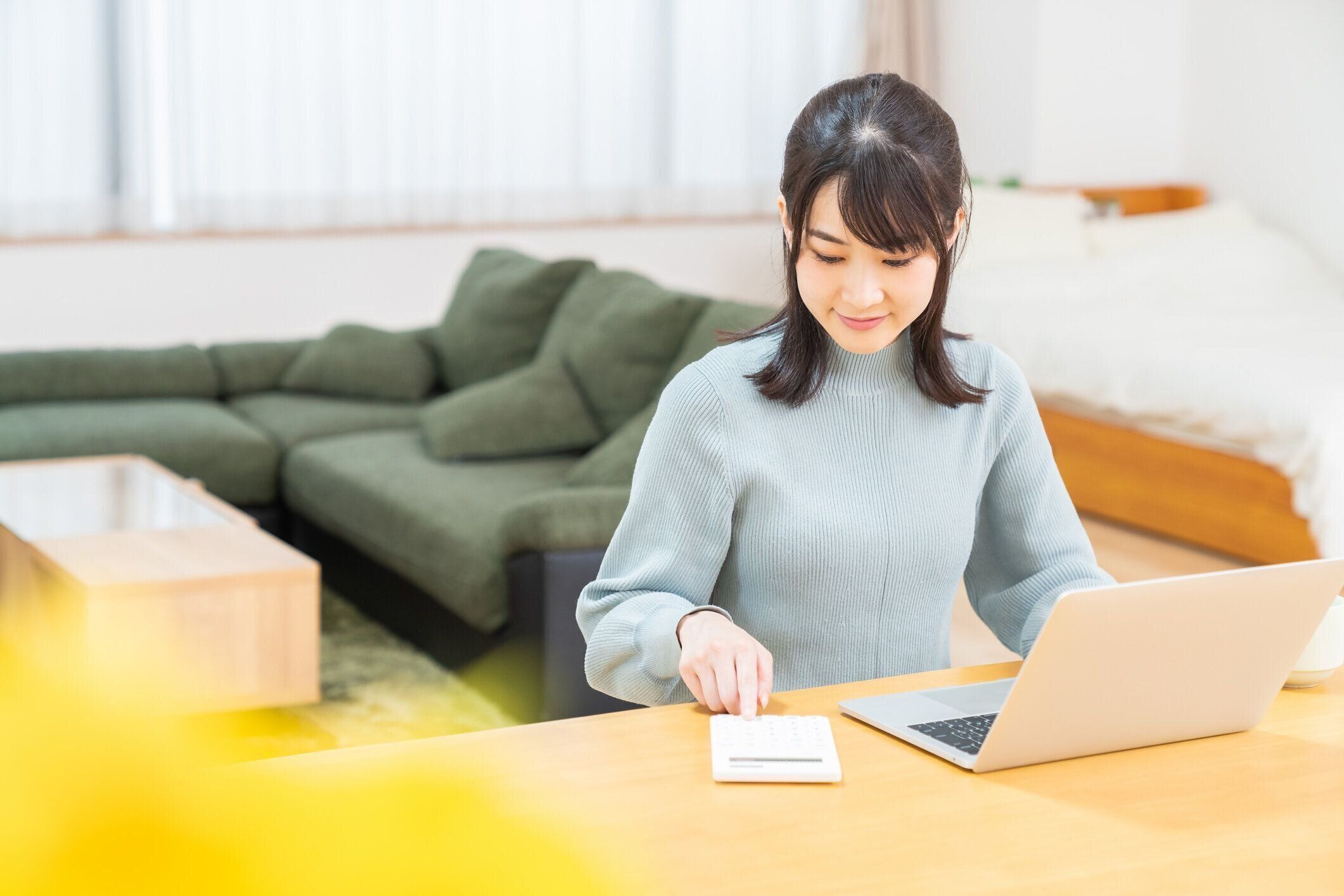 ラップトップ、電卓を使用して若いアジアの女性