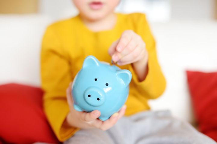 小さな男の子が貯金箱に硬貨を入れる