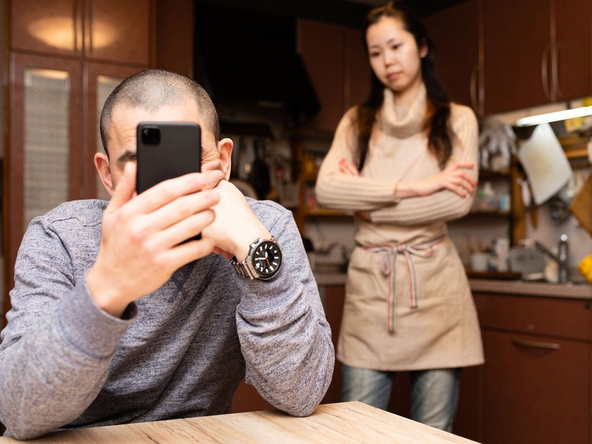 スマートフォンを見ている男性と怒っている女性