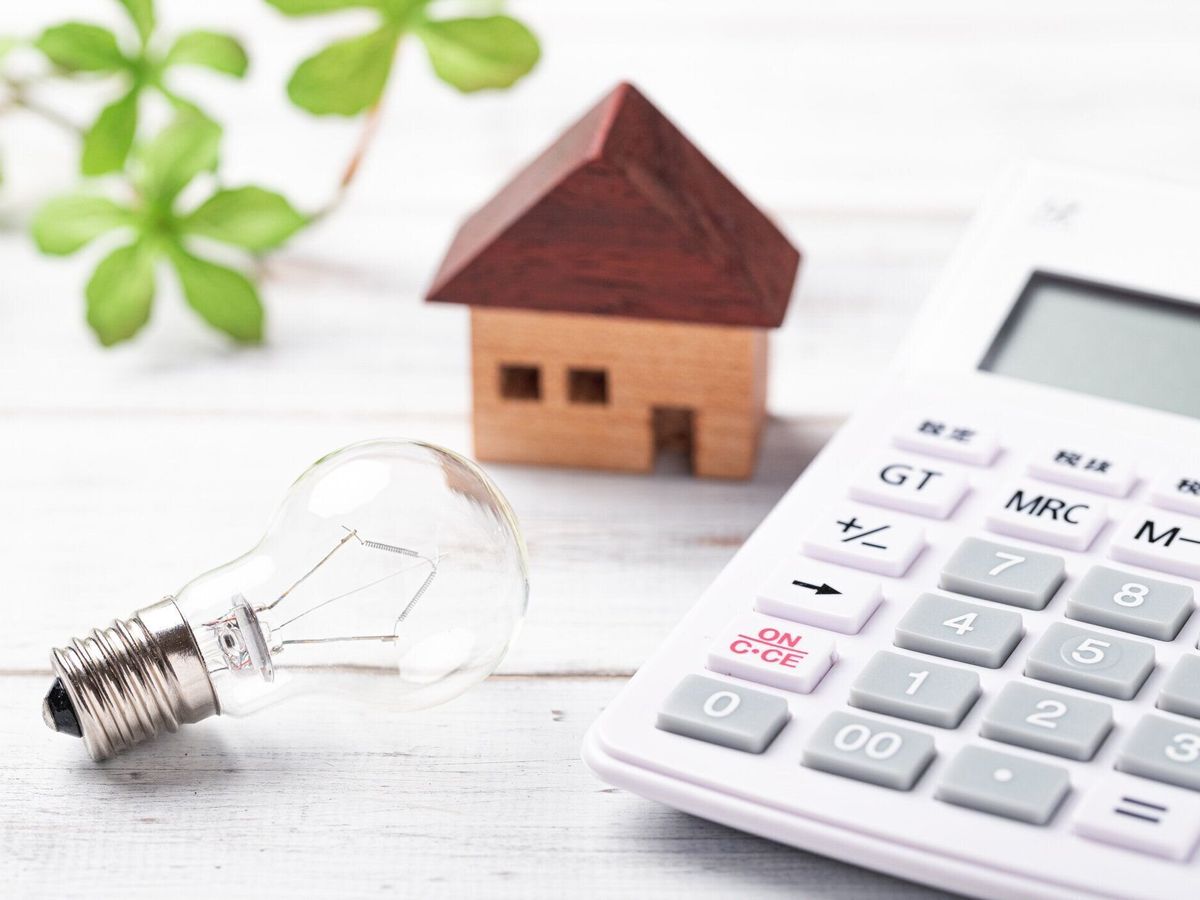 ホワイトボード上のミニチュア電球と電卓