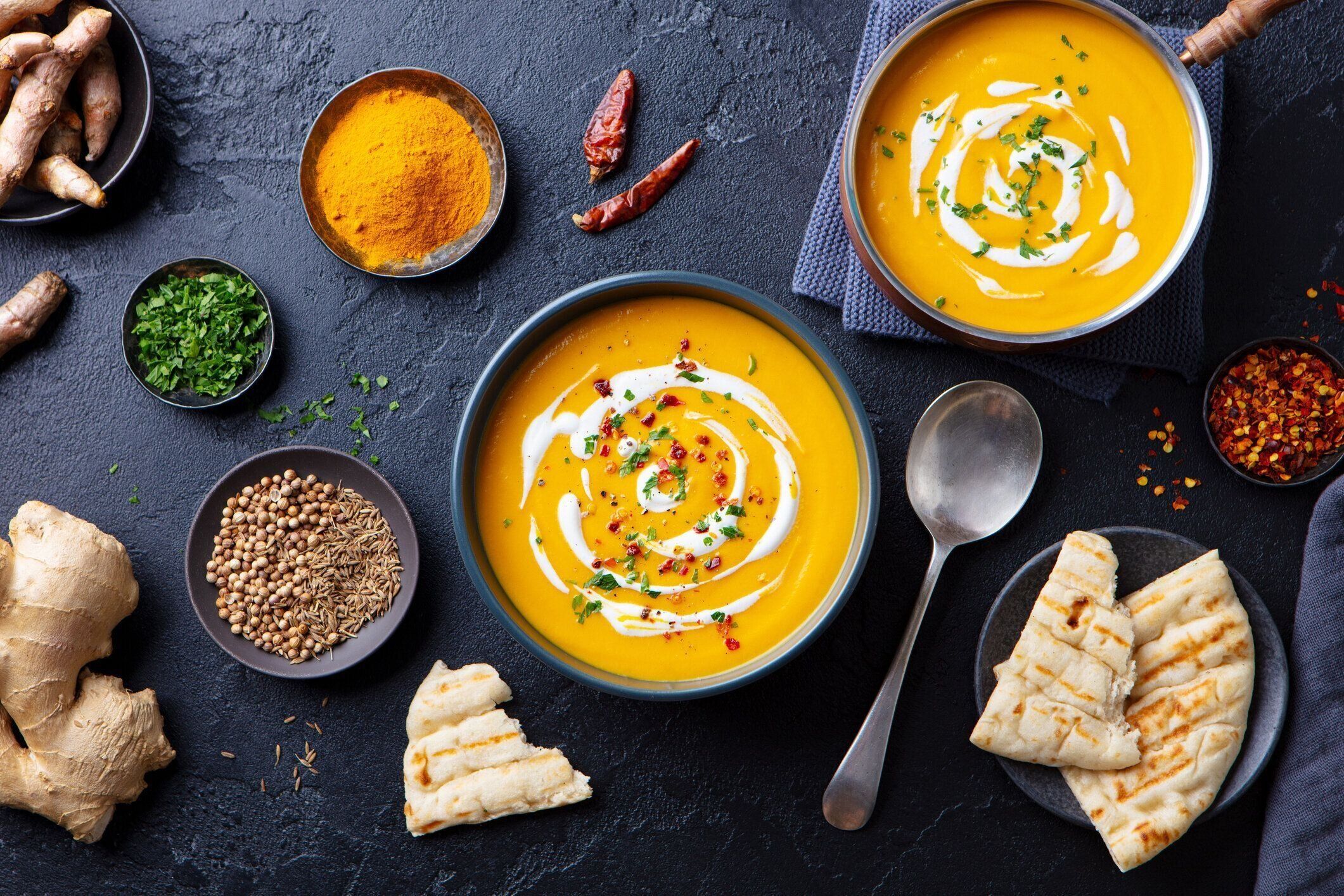 黒いボウルにスパイスを入れカボチャスープ。快適なデトックス食品。暗い背景。トップ ビュー。