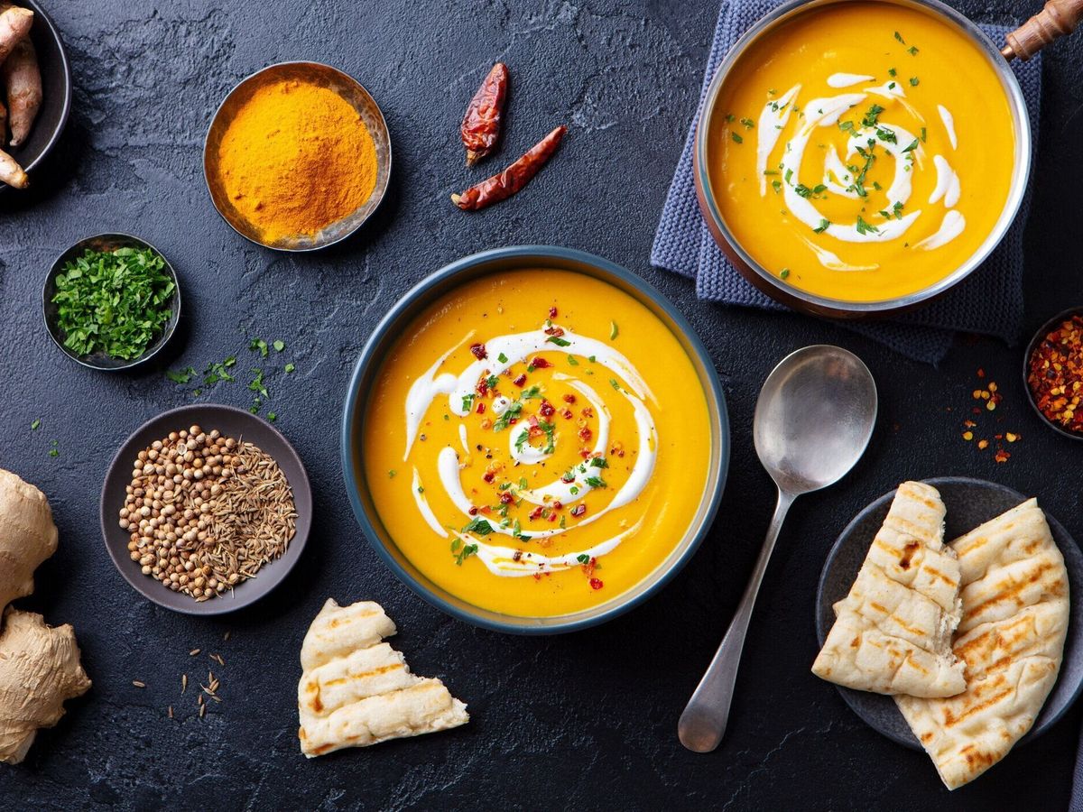 黒いボウルにスパイスを入れカボチャスープ。快適なデトックス食品。暗い背景。トップ ビュー。