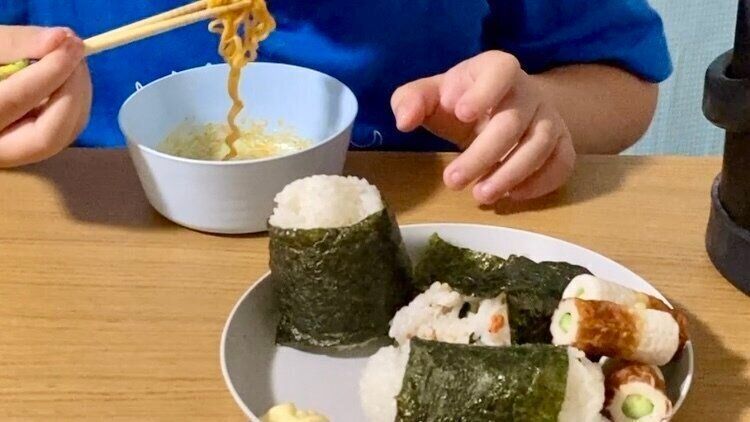 自分たちで作ったおにぎりと炒め麺を食べている子供