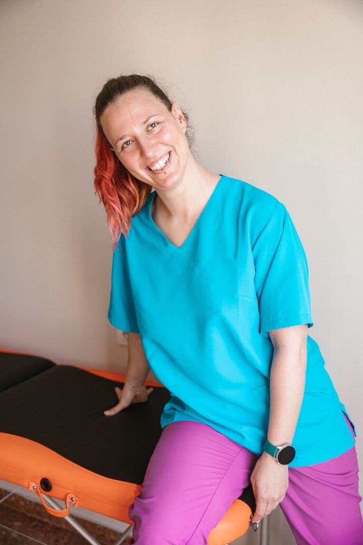 青いシャツと紫のズボンを着た女性がテーブルの上に座っている