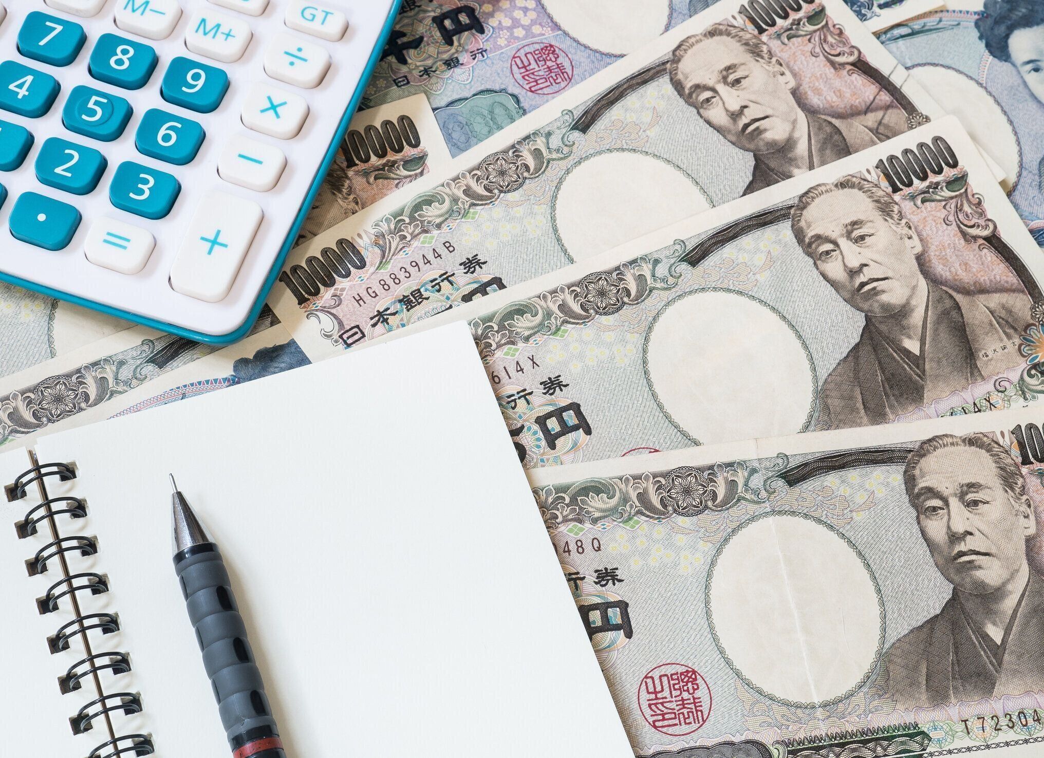 日本円通貨の電卓、ノート、鉛筆