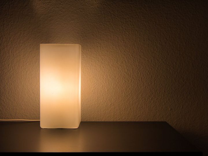 白い壁の前のドレッサーに輝く夜のテーブルランプ