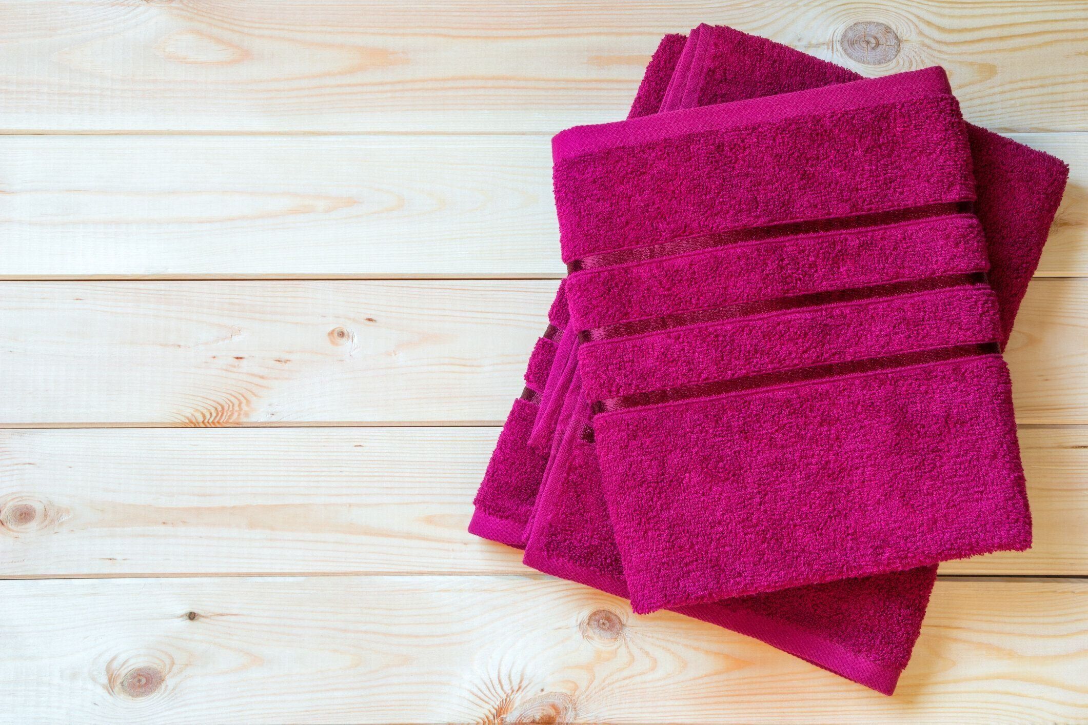 赤いテリータオルは、コピースペースと木製のテーブルに折り畳まれています。トップビュー。