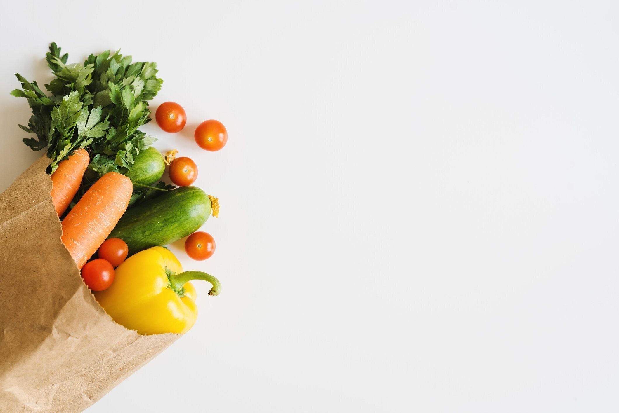 白い背景、トップビューにエコフレンドリーな紙袋に新鮮な野菜やハーブ。食品の配達。食料品の買い物