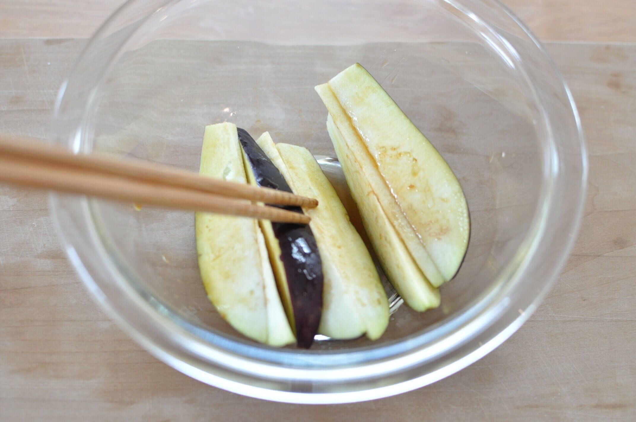 なすを耐熱ボウルにいれ、焼き肉のタレを絡める様子