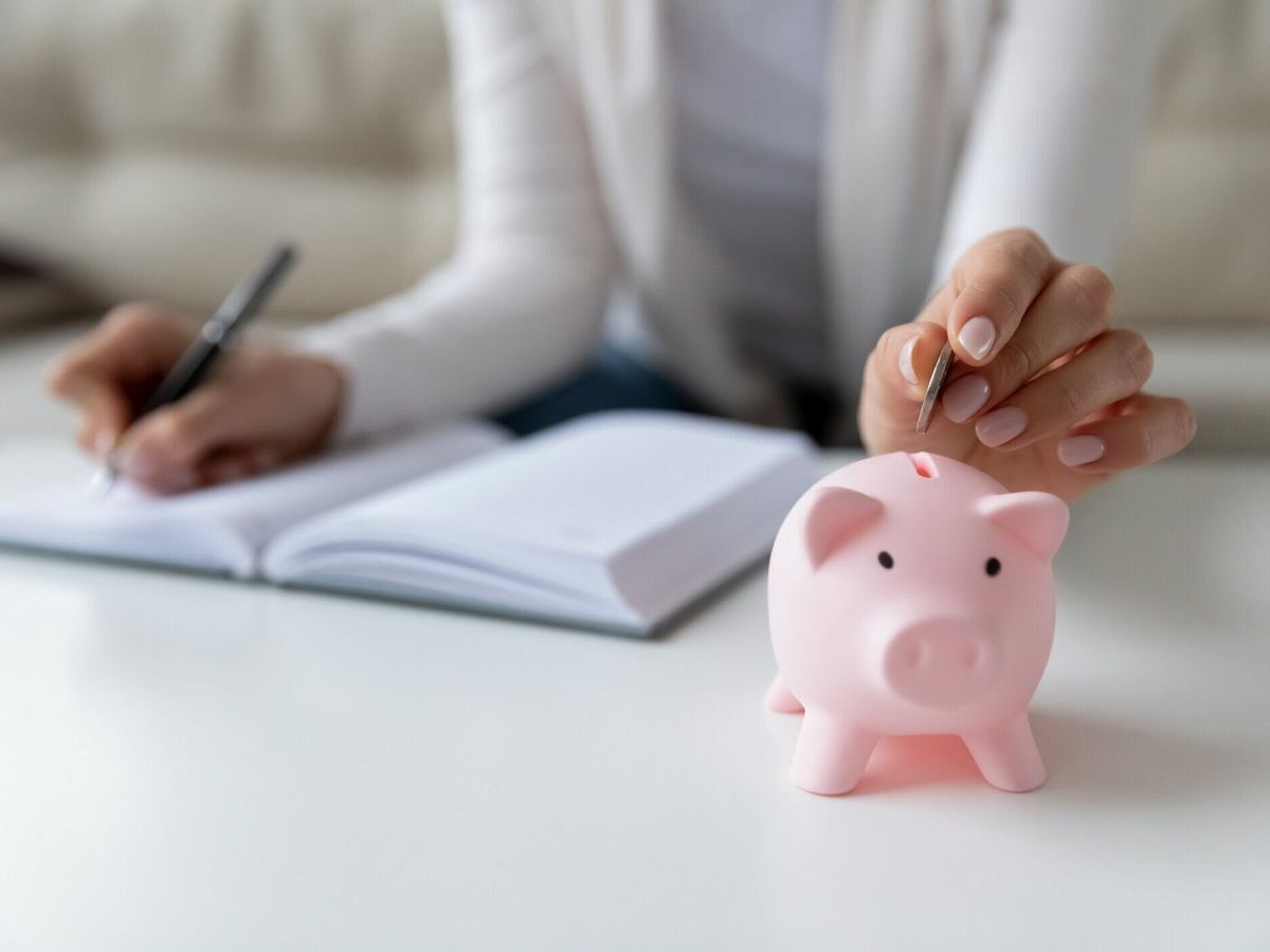 毎日の費用を書く倹約家の女性は、貯金箱にコインを入れて