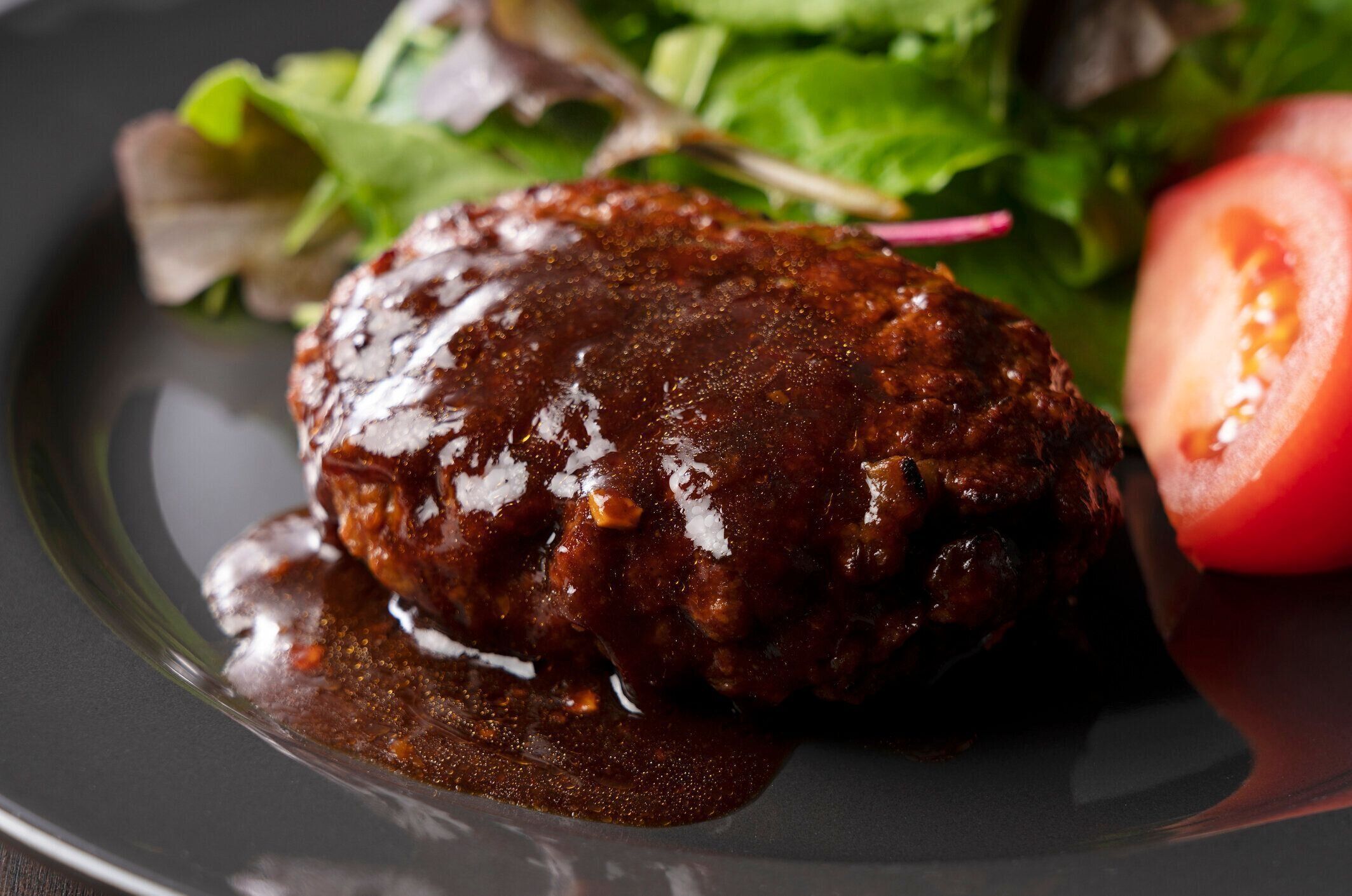 テーブルの上に置かれた皿の上に置かれたデミグラスソースとハンバーガー