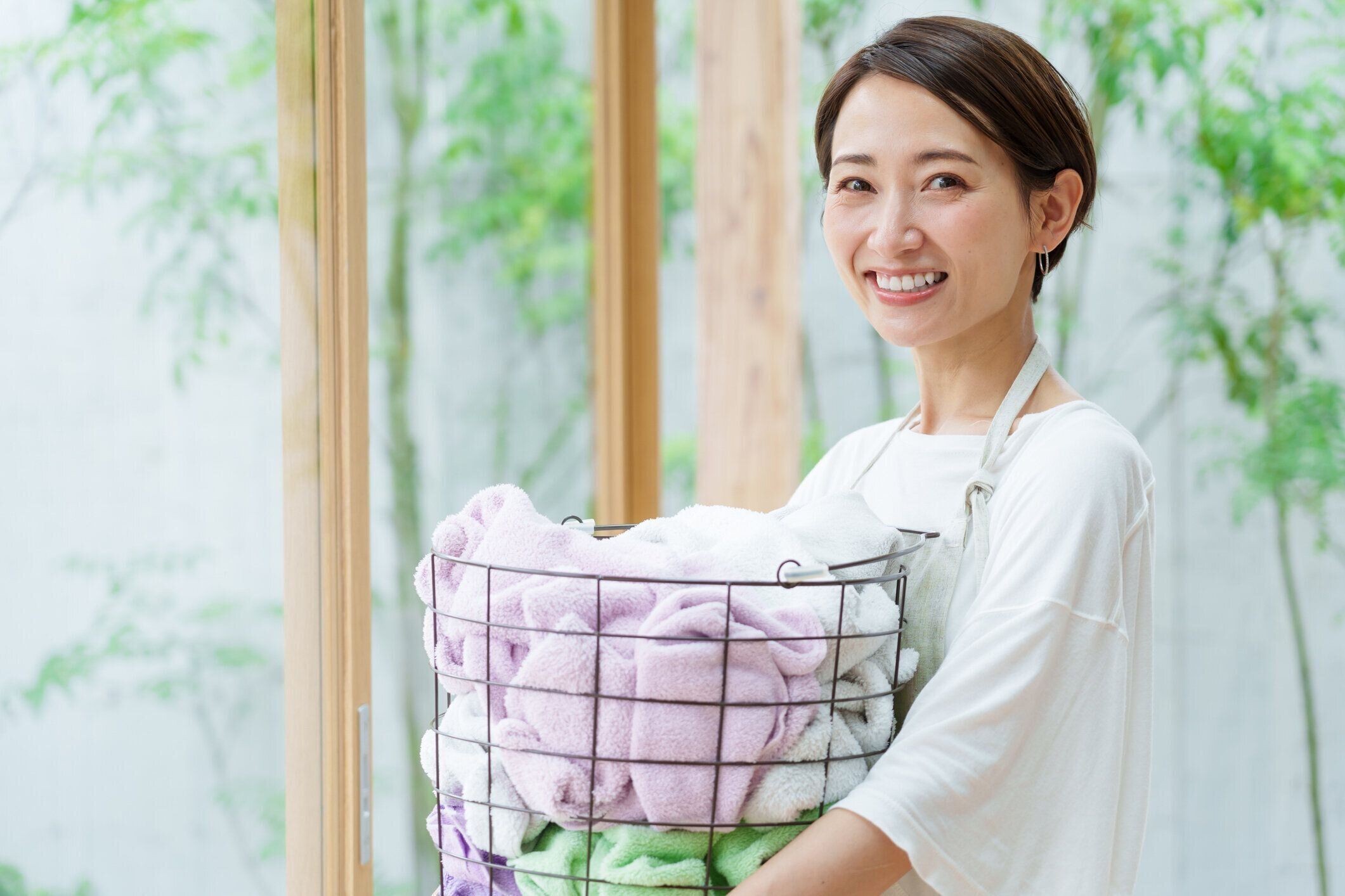 リビングルームで洗濯かごを持つ魅力的なアジア人女性