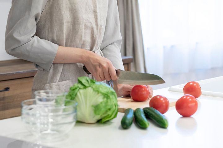 台所で野菜を切る若い女性の手