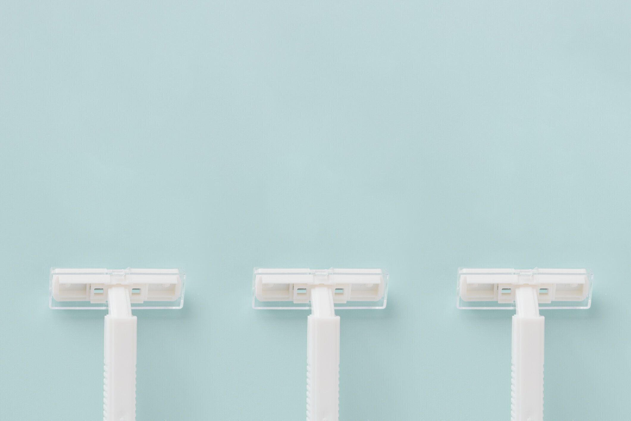 青い背景に使い捨ての白いプラスチックかみそりコピー スペース