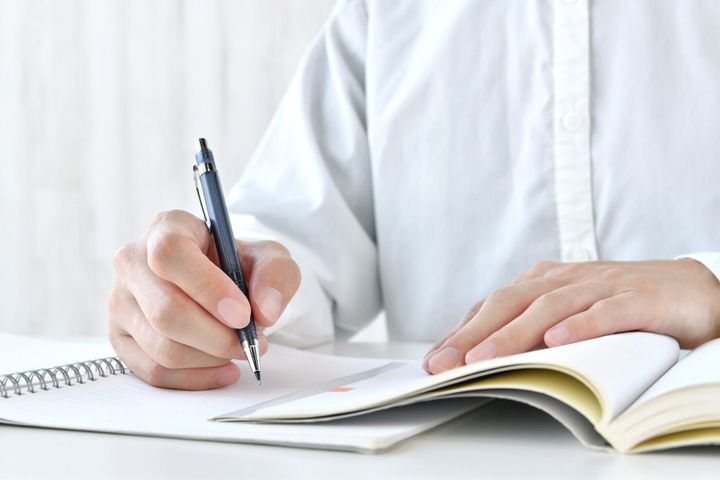 ノートや教科書で一生懸命勉強する人間の手