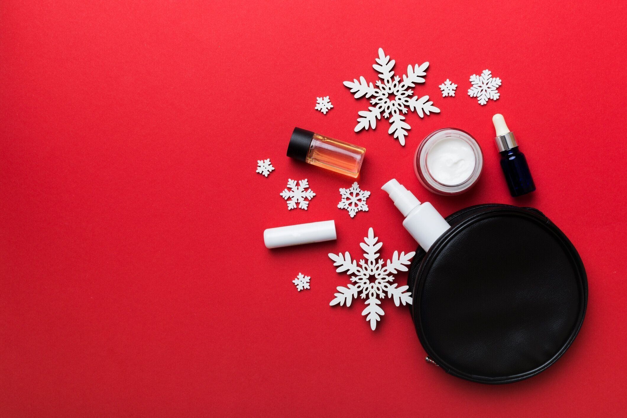 クリスマスフラットは、色の背景に化粧品袋に化粧化粧品で横たわっていました。トップビュー新年美容コンセプト