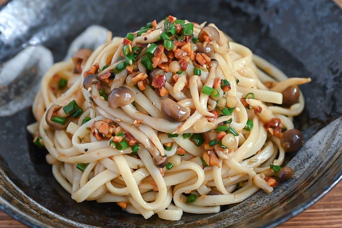黒い皿に盛られたしめじの和えうどん