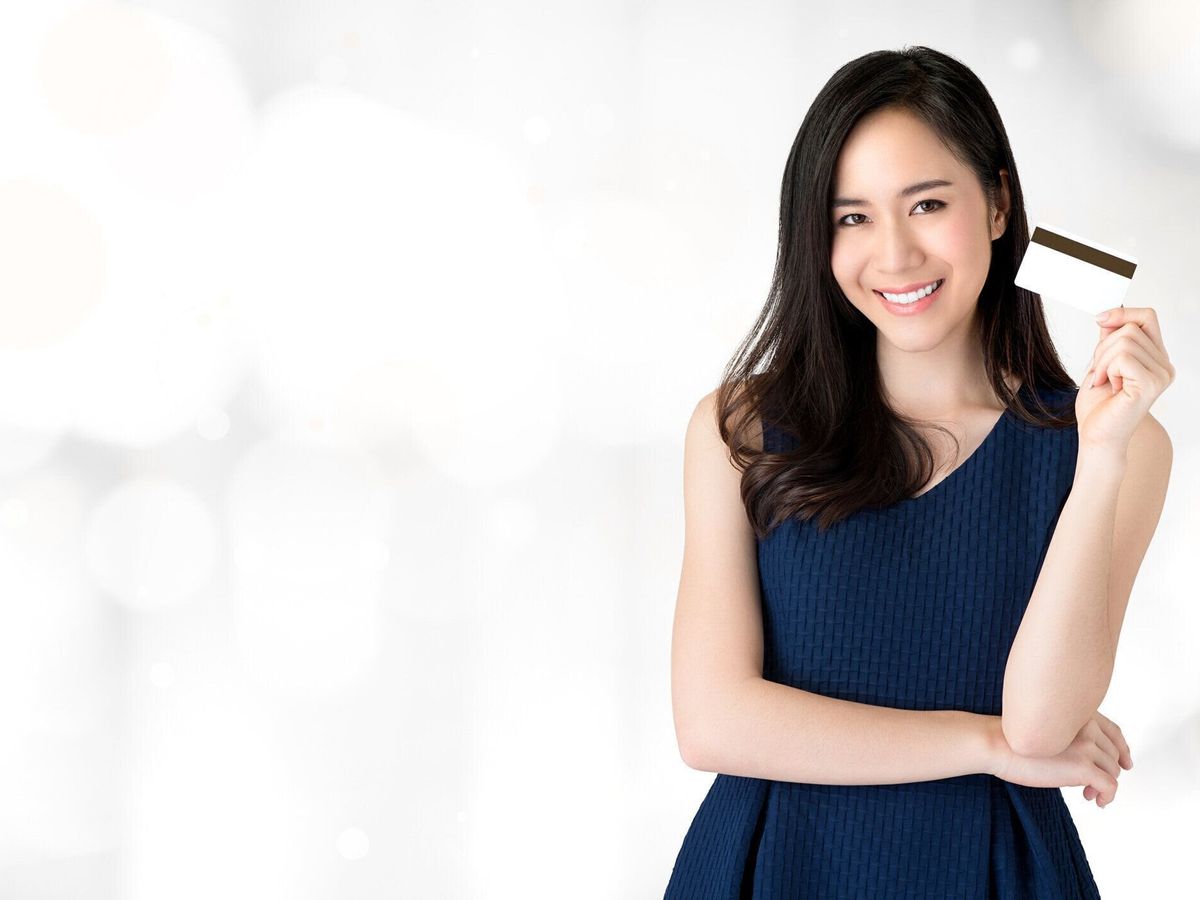 手にクレジット カードを提示若い笑顔の美しいアジア女性