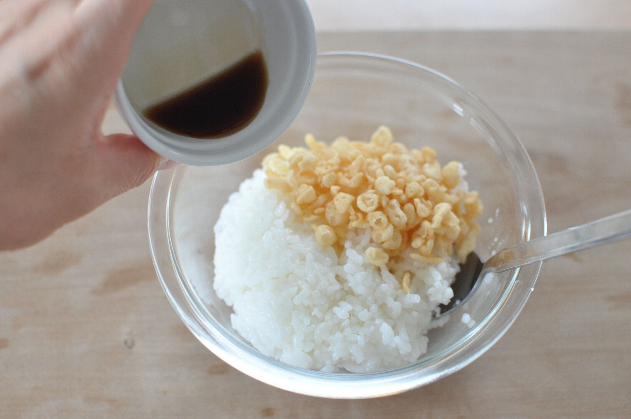 ご飯と揚げ玉を入れたご飯に、麺つゆを加える様子