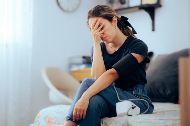 吐き気と気分が悪くなる血圧を測る女性