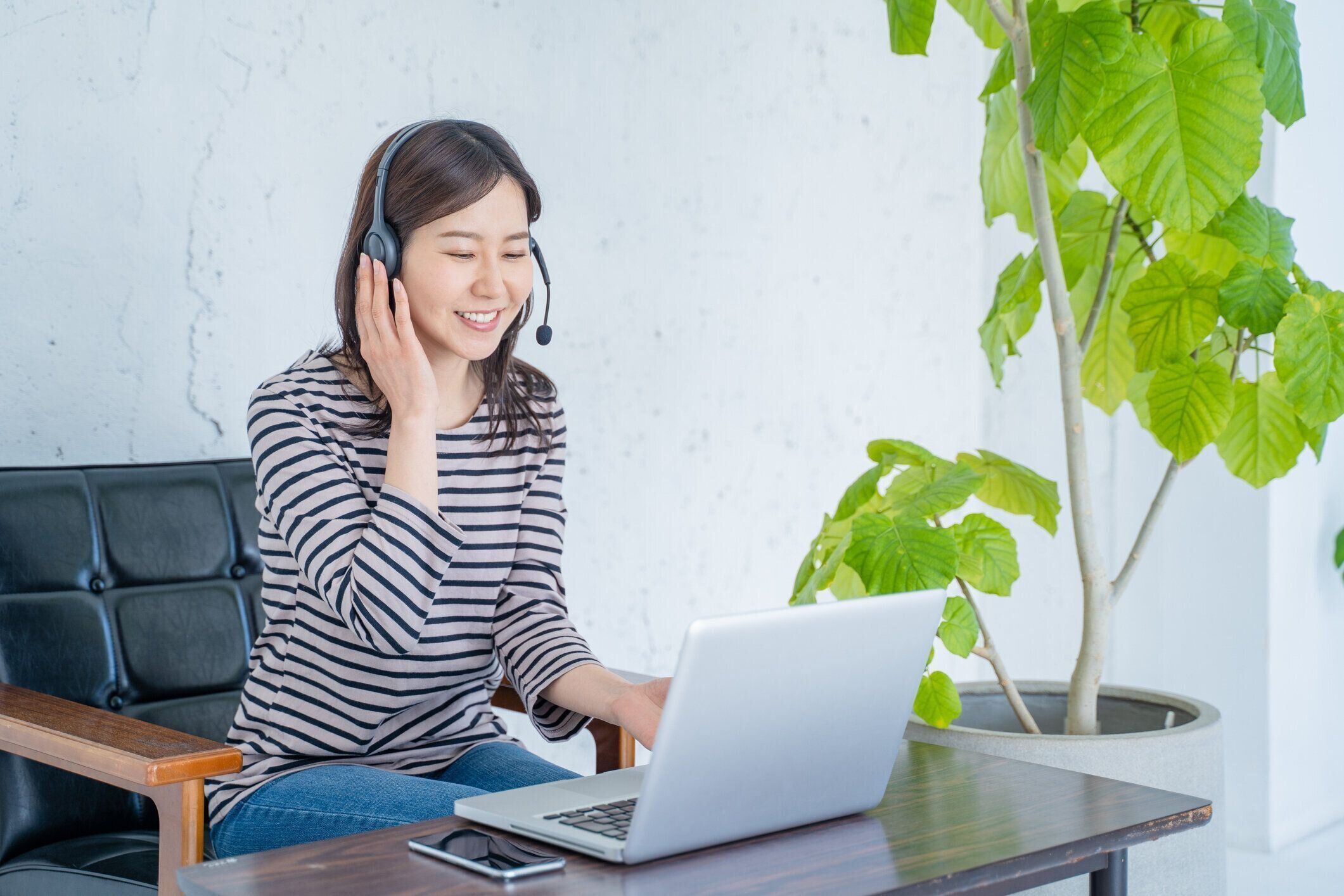 ヘッドセットとビデオチャットで自宅で仕事をする女性。