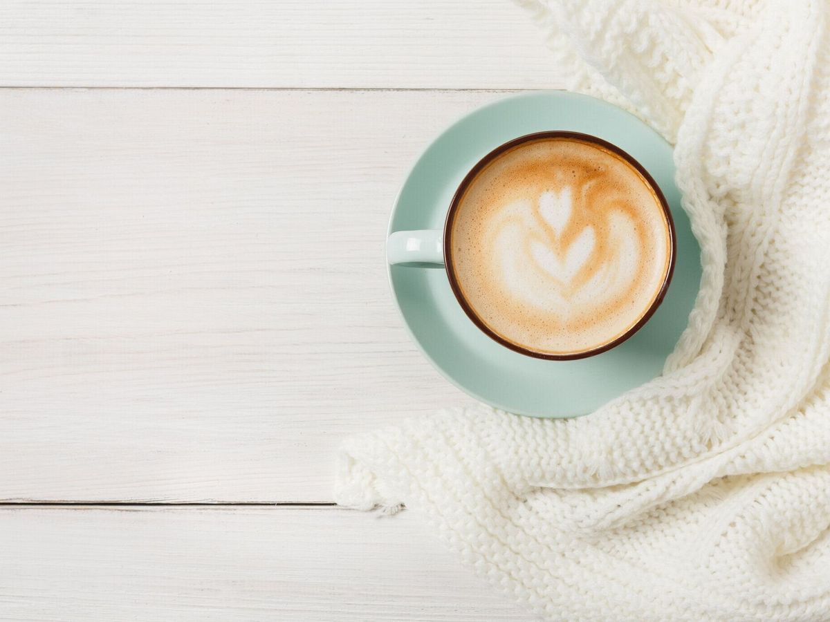 白い木の背景に冬のカプチーノコーヒーカップ