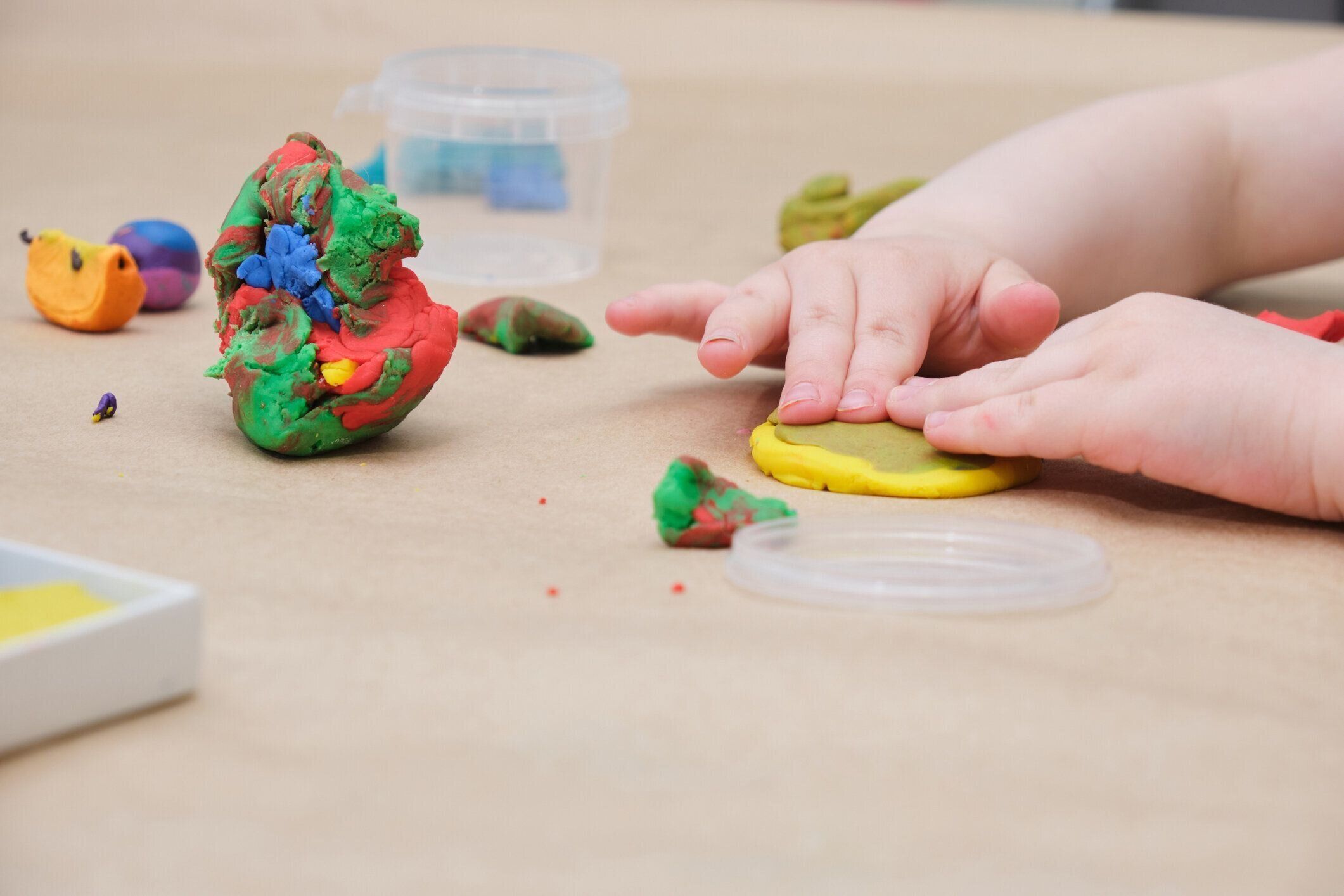 テーブルでプラスチックから彫刻子供の手、女の子はプラスチックで遊ぶ