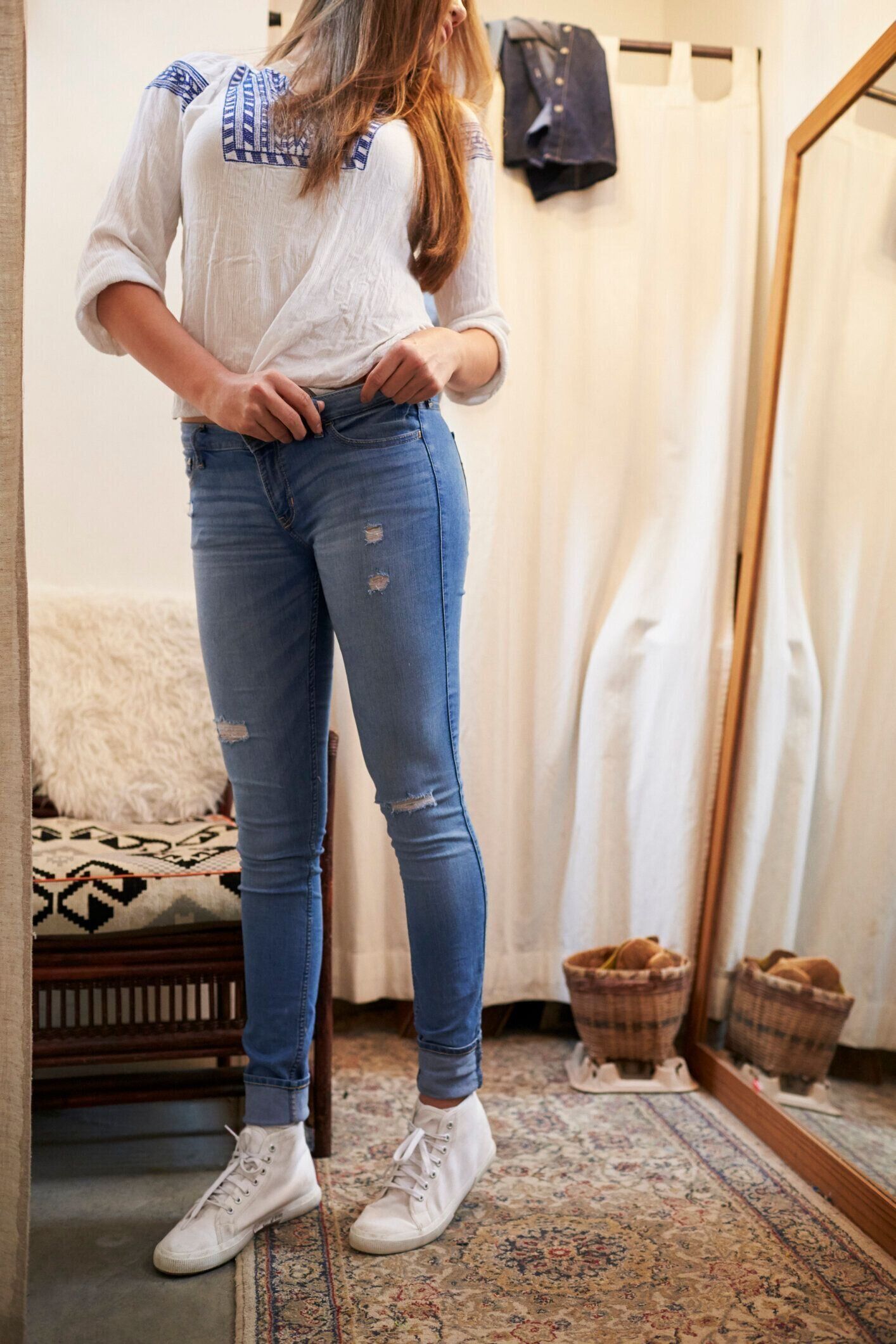 鏡を見ている更衣室でジーンズを試している女性