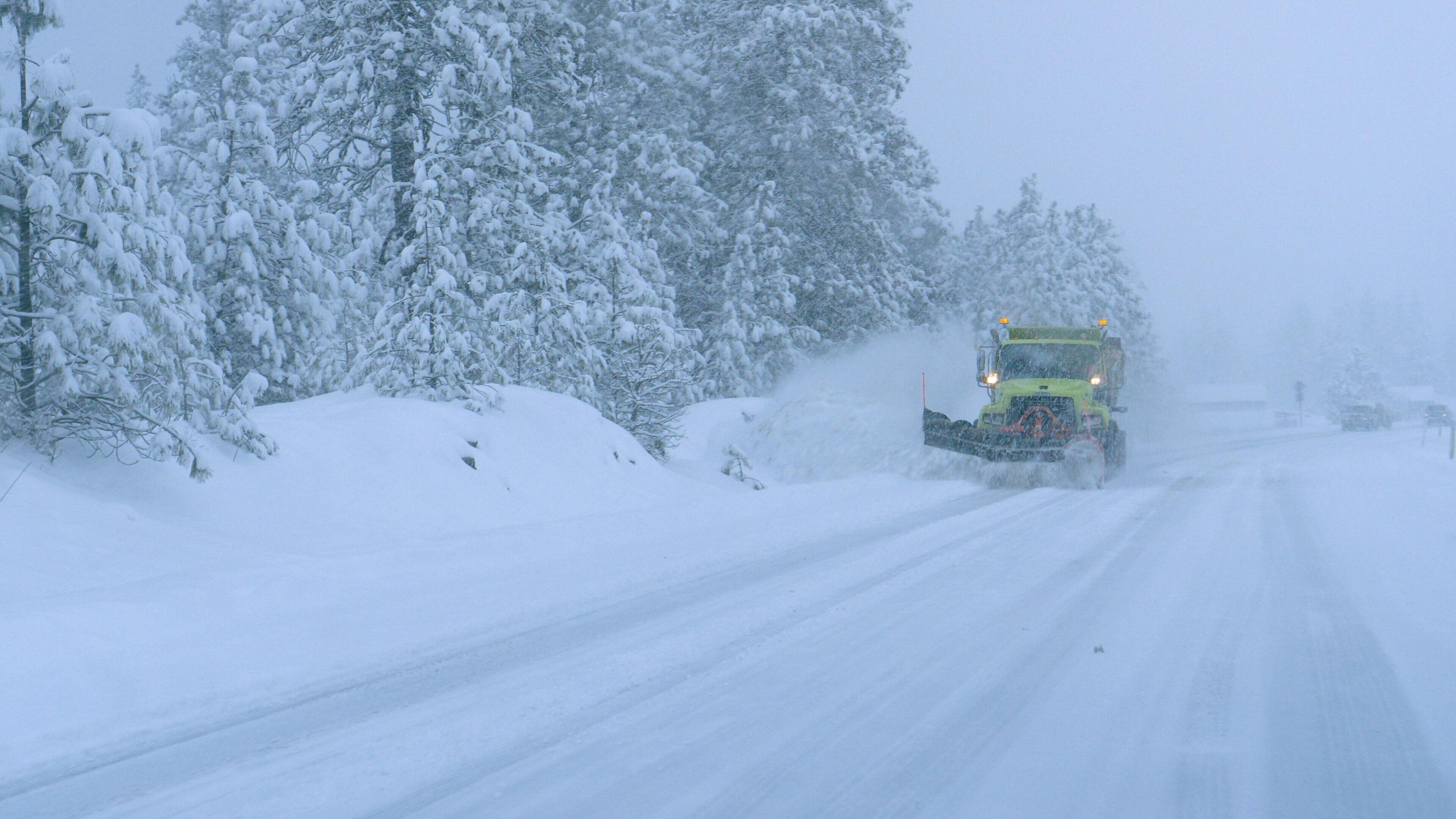 クローズアップ:トラックは恐ろしい吹雪の間に雪の田舎道を耕します。