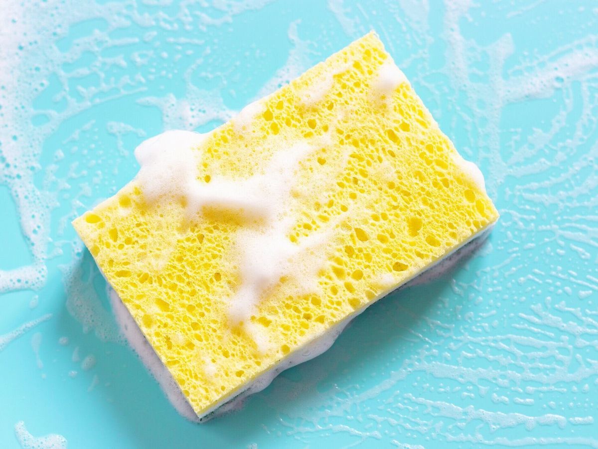 青い背景のクローズアップに泡を持つ黄色のスポンジ。