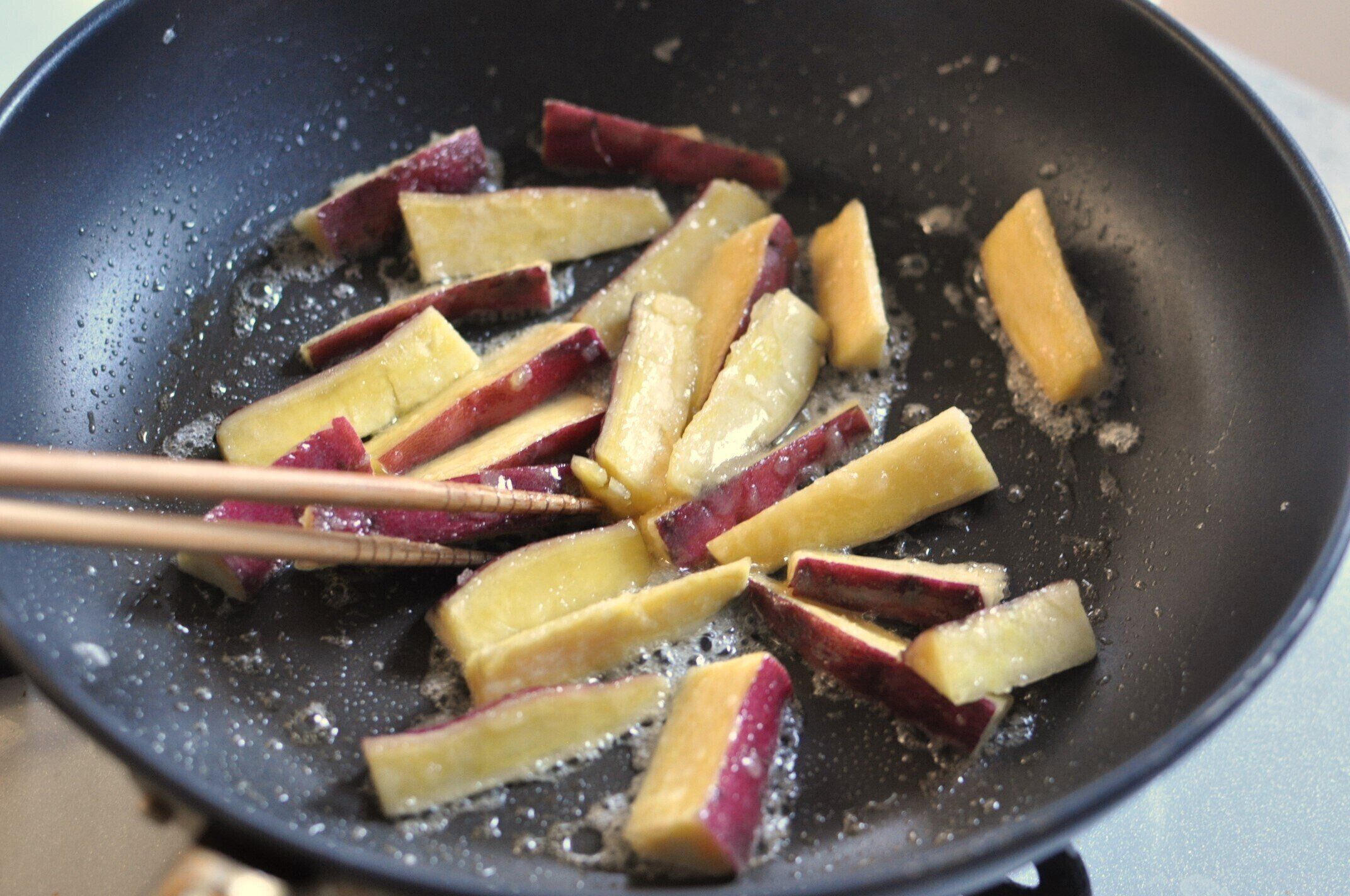 砂糖とバターをさつまいもに絡ませながら炒める様子