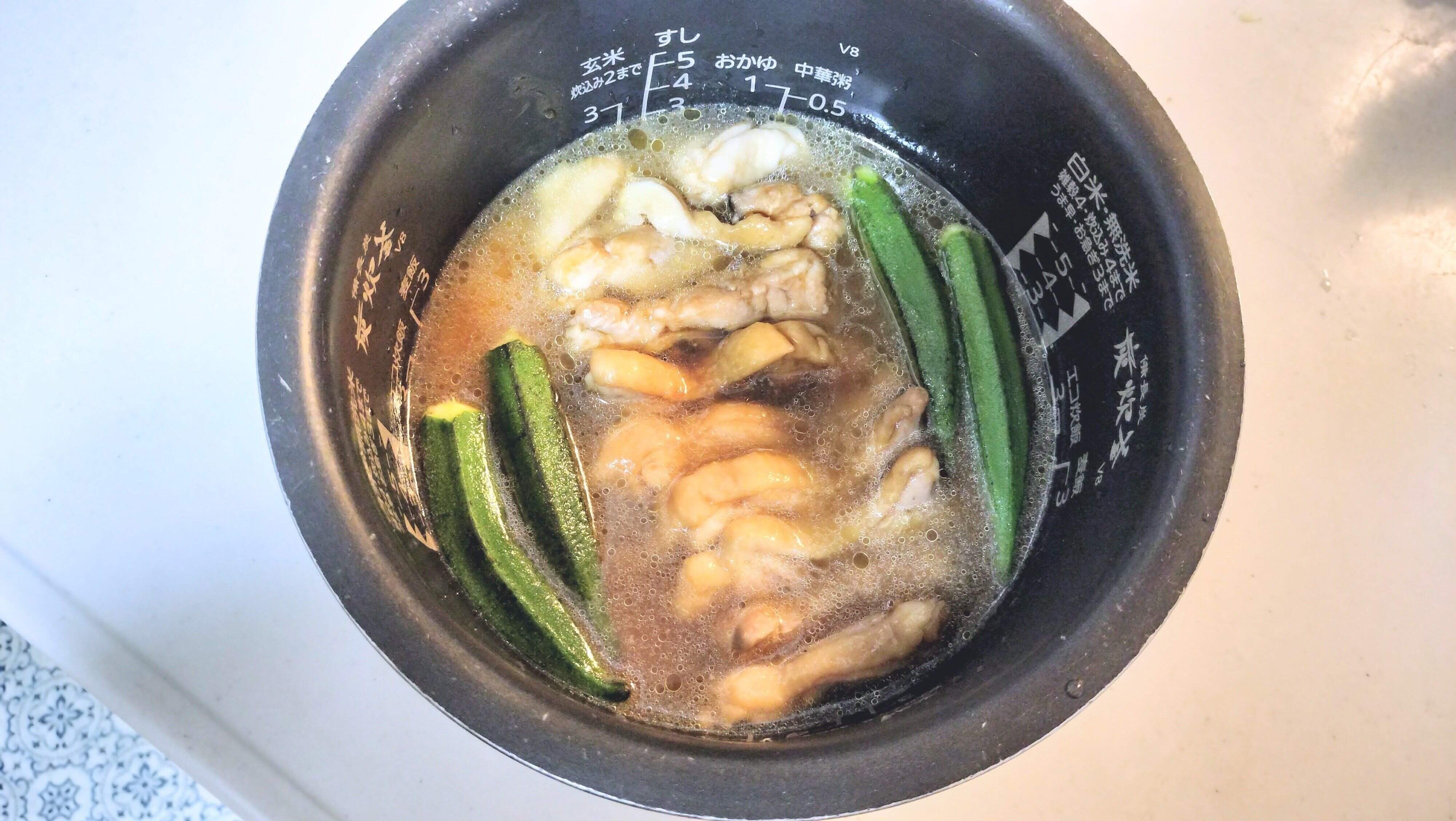 火にかけた鶏肉とたれ、おくらを一緒に炊き込む