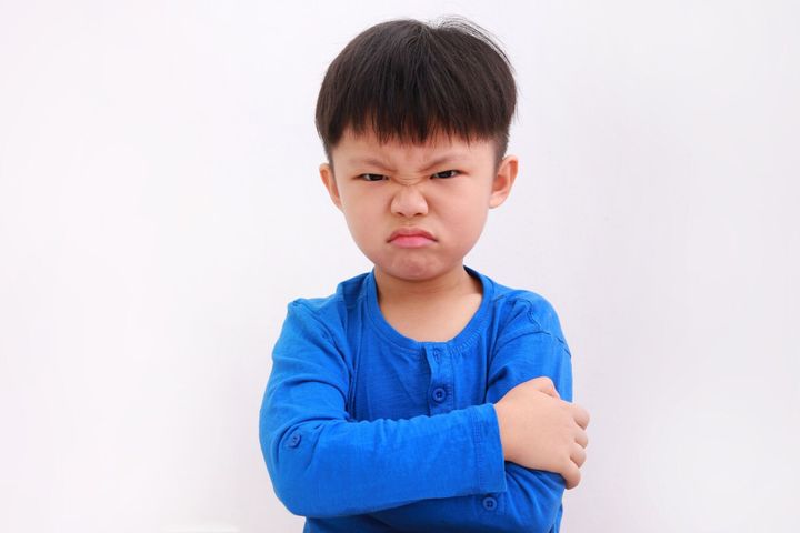 白い背景に孤立した腕を持つ怒っている少年