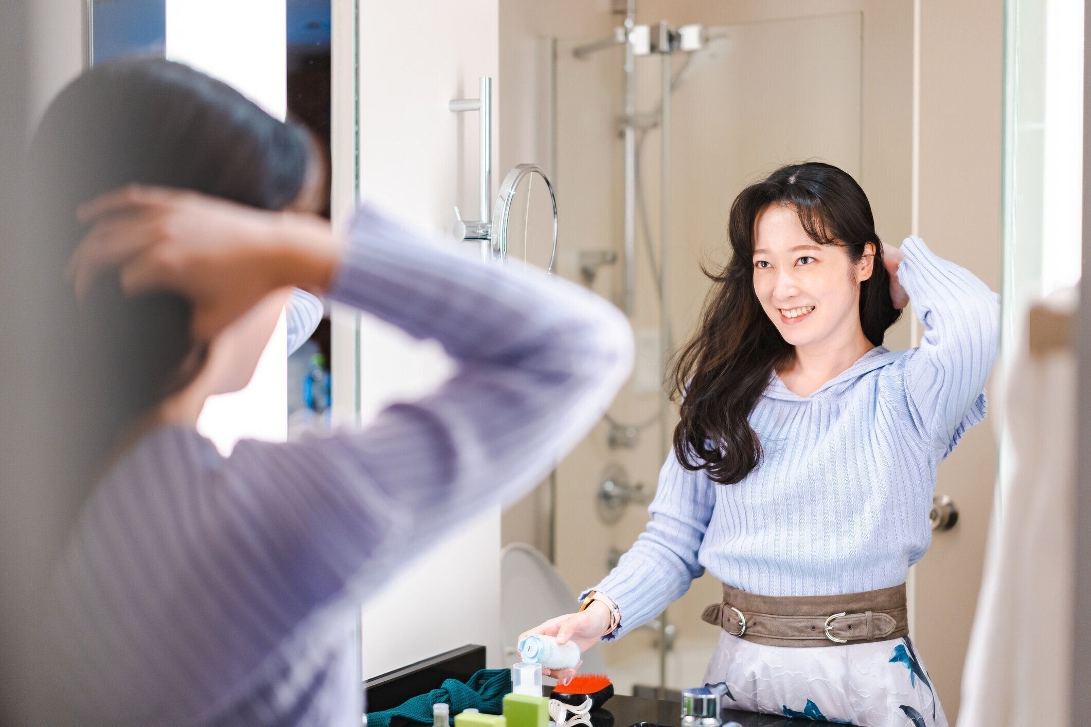 鏡の前で髪をしている若い女性