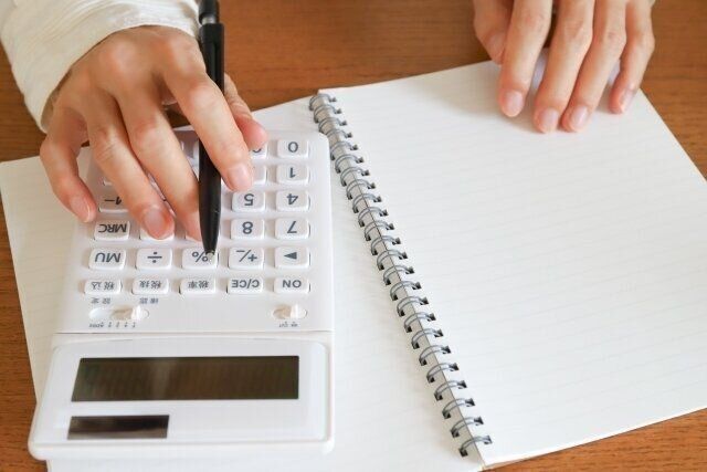 電卓で計算している手元と広げられたノート