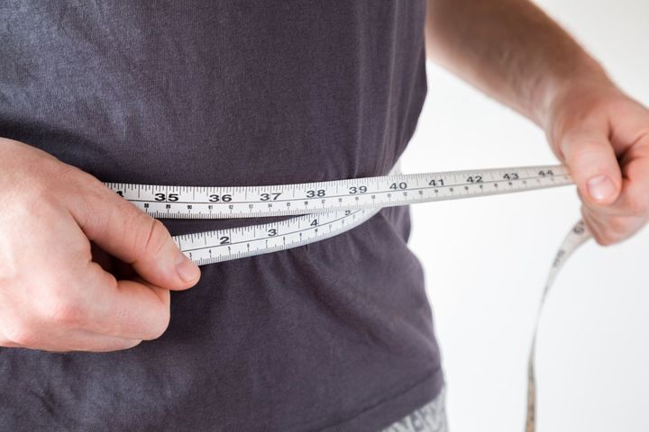 スリムな男を腰を測定します。健康、痩身、ボディ重量損失の概念。体を気にします。
