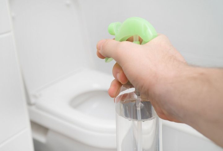 男性の手が自宅トイレの芳香剤を噴霧します。