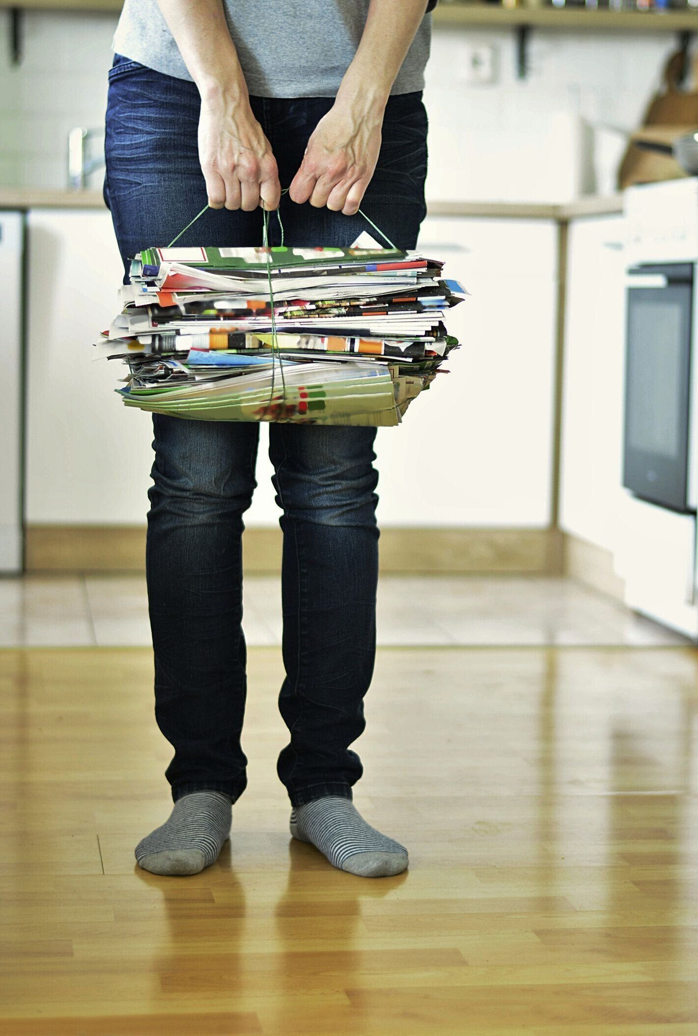 自宅でリサイクルのために古い雑誌を持っている女性