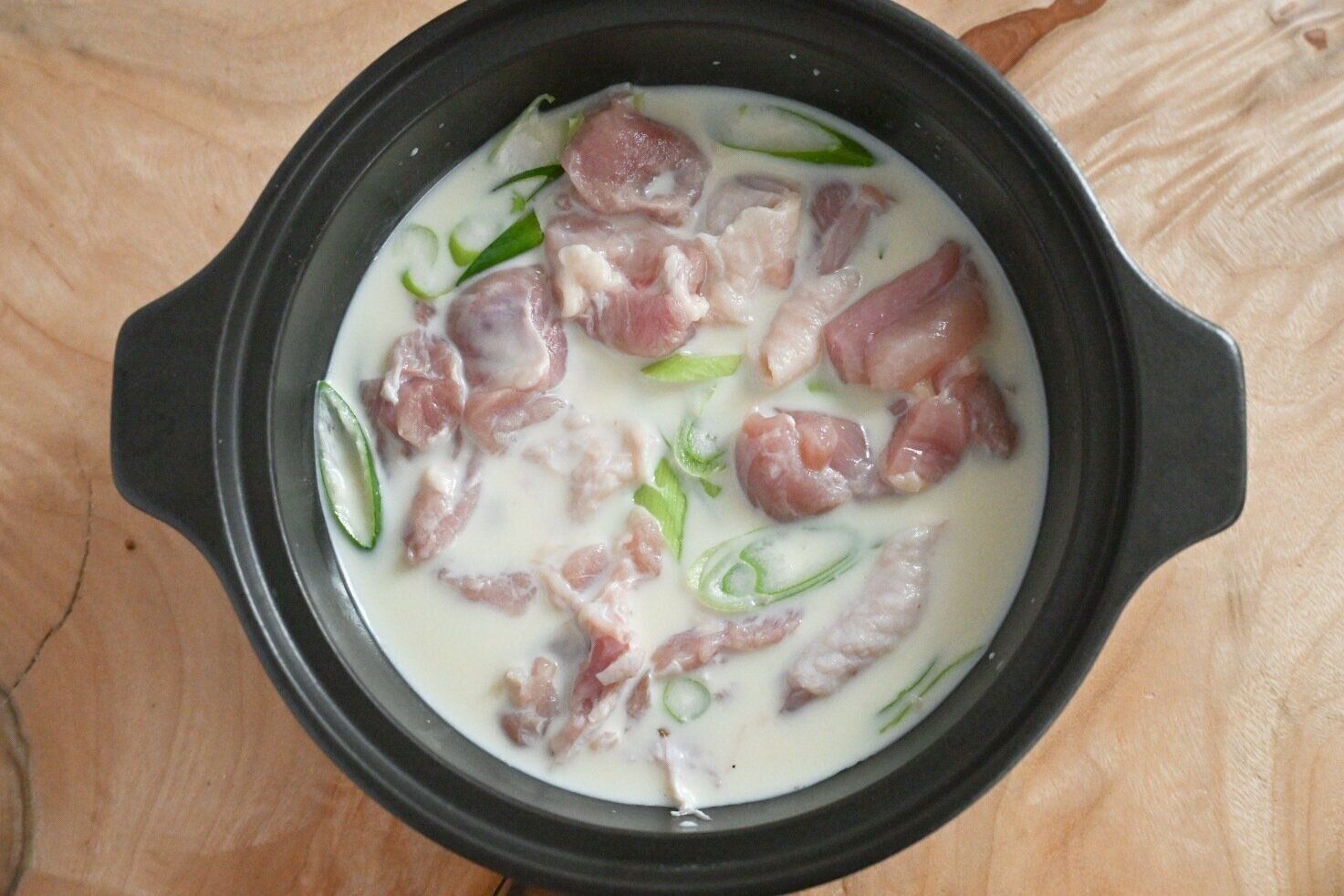 鍋に入った鶏もも肉と長ねぎと豆乳