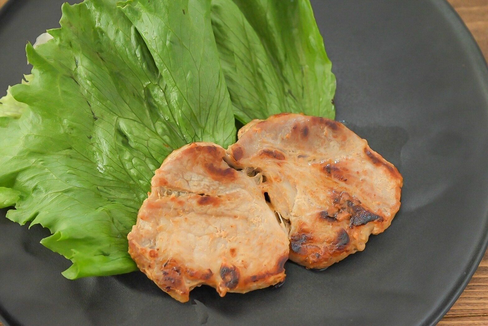 黒い皿に盛られた加熱した豚肉の粕漬け焼き