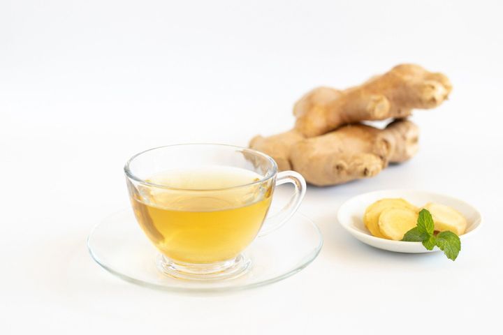 白い背景に生姜の根を持つお茶。健康飲料のコンセプト。