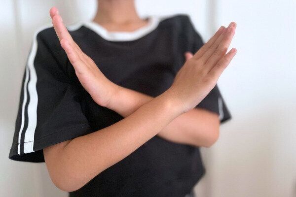 子どもが「イヤ」と手でジェスチャーして伝えている様子