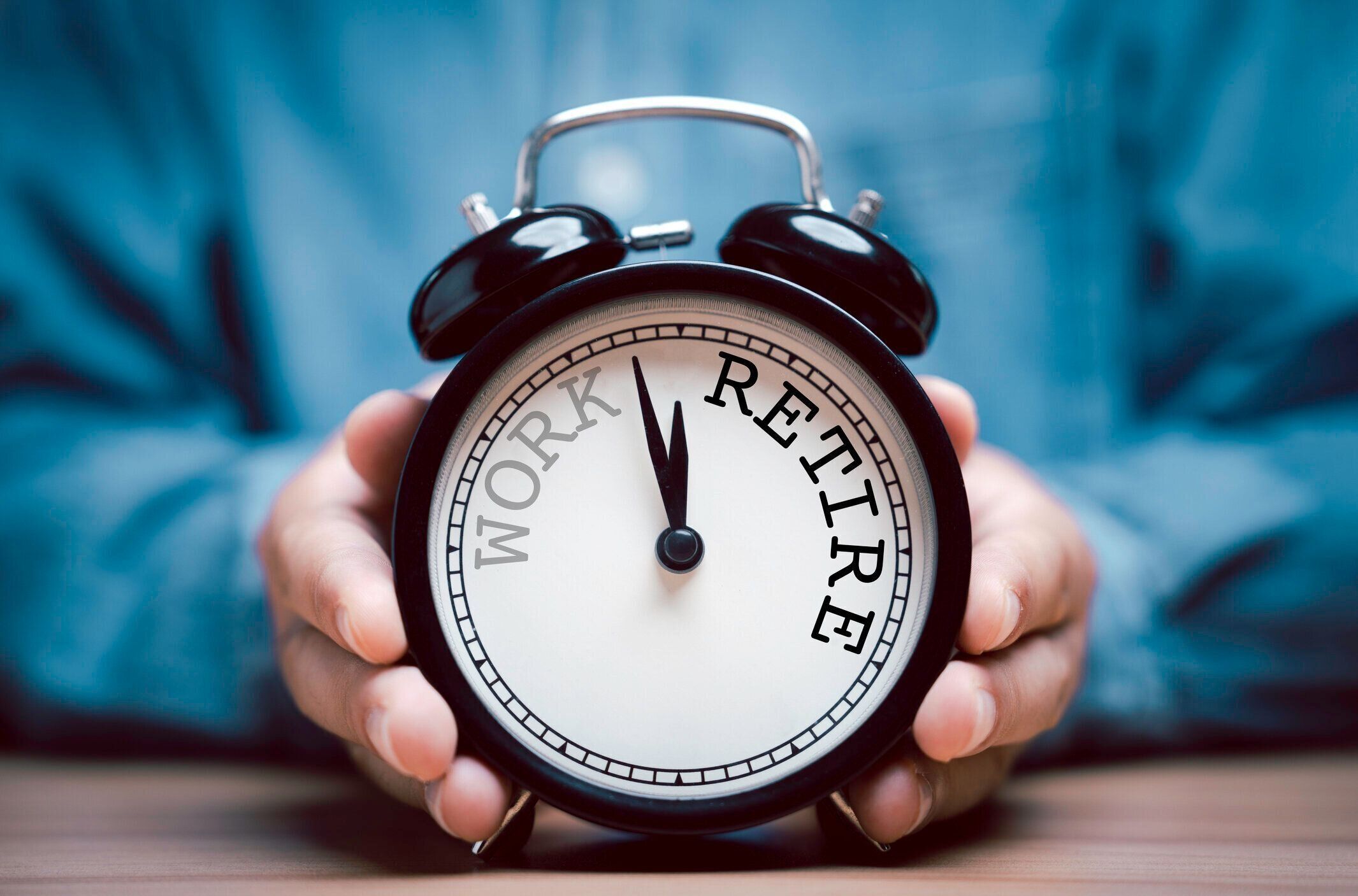 仕事から退職までの時計回りのカウントダウンを持つ黒い目覚まし時計を持つ実業家。