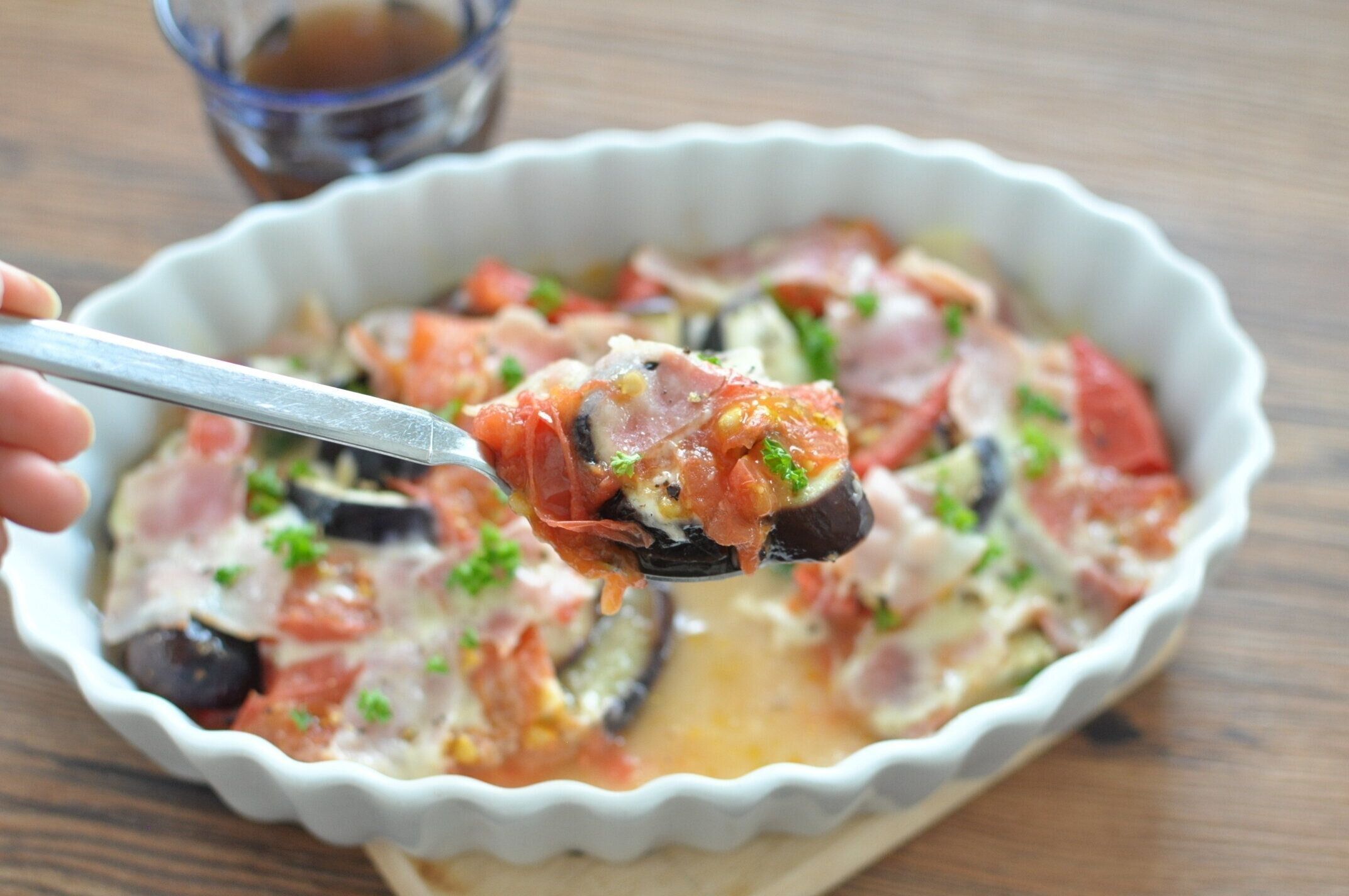 なすトマベーコンチーズ焼きをスプーンですくっている様子