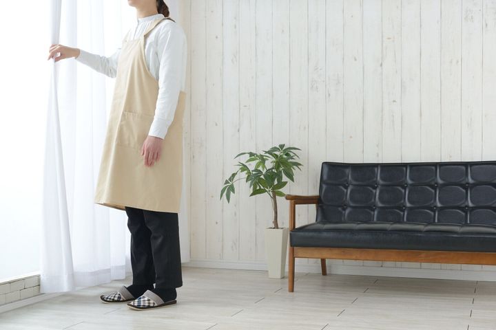 リビングルームでの女性のオープニングカーテン